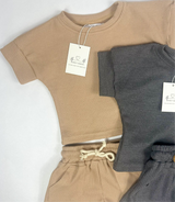 Two toddler waffle outfits, one beige and one gray, with tags on a white background.
