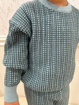 Blue and navy checkered sweater worn by a child against a light background. Cropped to only show sweater.